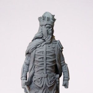 Può includere: Una figura scheletrica grigia che indossa una corona e un'armatura a maglia. La figura tiene una spada nella mano destra. La figura è una miniatura stampata in 3D.
