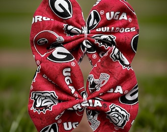 May include: Red and black fabric bow with the University of Georgia logo and the words "UGA Bulldogs".