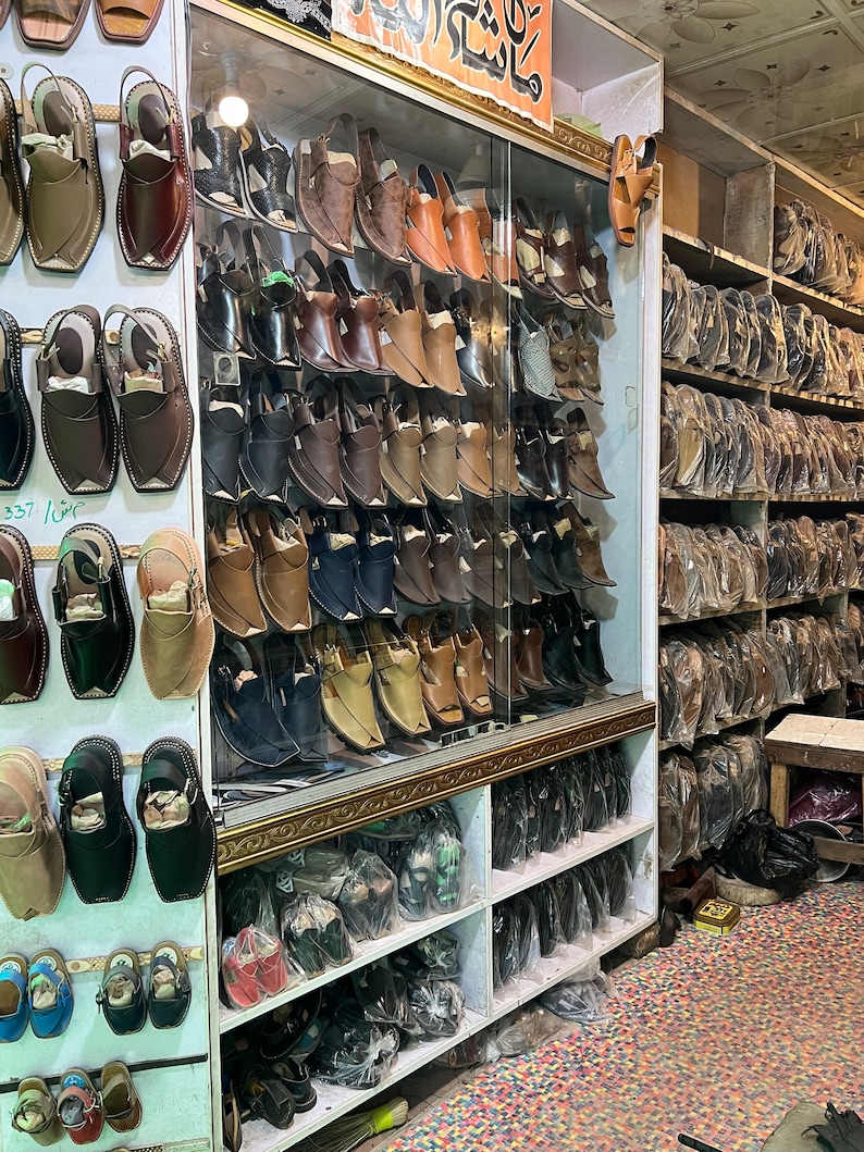 May include: A shoe store display featuring a variety of leather shoes in shades of brown, black, and tan. The shoes are displayed on shelves and in a glass cabinet, showcasing different styles of footwear.
