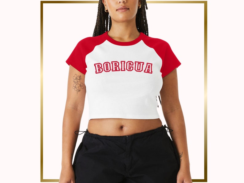 Puede incluir: Una camiseta blanca recortada con mangas rojas y la palabra "BORICUA" impresa en rojo en la parte delantera.