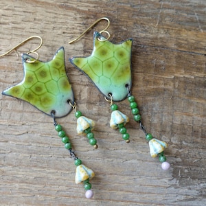 Puede incluir: Pendientes hechos a mano con un dise&ntilde;o inspirado en la naturaleza. Los pendientes presentan colgantes verdes en forma de hoja con un patr&oacute;n texturizado, acentuados por cuentas verdes y peque&ntilde;os dijes de flores. Los ganchos para las orejas son dorados.