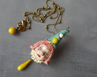 Colgante de cerámica hecho a mano con forma de cabeza de muñeca de circo.