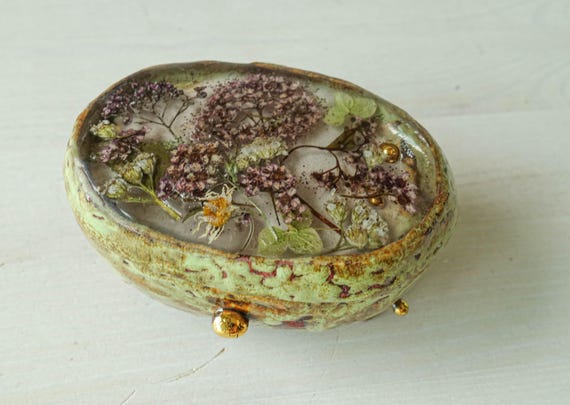 Real pressed flowers embedded into a handmade ceramic ring box lid — botanical preservation meets functional jewelry storage.