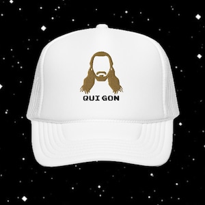 Peut inclure: Casquette de camionneur blanche avec un dos en filet et un devant uni. Le devant présente un motif brodé doré d'une figure aux cheveux longs et le texte "QUI GON". Cette casquette est de style classique, adaptée au port décontracté.