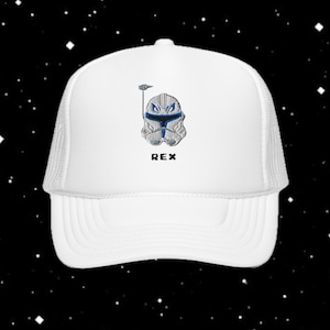 Op de afbeelding: Witte truckerpet met een gedetailleerde illustratie van een helm met blauwe accenten en de naam "REX" in zwart. De pet heeft een mesh rug en een gebogen klep.