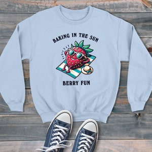 Fresa tomando el sol horneando en el sol estilo de dibujos animados sudadera unisex, suéter gráfico retro, estilo moderno y divertido