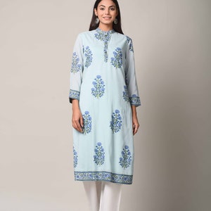 May include: A light blue long-sleeved kurta with a floral print in shades of blue and green. The kurta has a mandarin collar and a button closure. The model is wearing white pants and is standing against a white background.