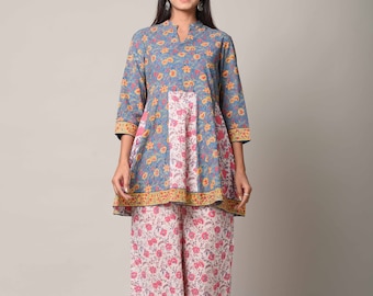 May include: A woman is wearing a blue and pink floral print top with a matching pair of palazzo pants. The top has a mandarin collar and three-quarter sleeves. The pants have a wide leg and a floral print.