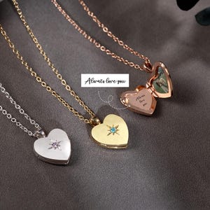 May include: Four heart-shaped pendant necklaces in silver, gold, and rose gold. Each necklace has a delicate chain. One silver pendant has a starburst design, one gold pendant has a blue gemstone, and one rose gold pendant opens to reveal a photo. The text "Always love you" is also visible.