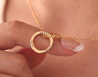 May include: A gold-toned necklace featuring a circular pendant engraved with the names Jack and Emily. The pendant is suspended from a delicate gold-toned chain, creating a simple and elegant piece of jewelry that rests against the skin.