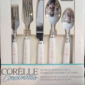 Pode incluir: Um conjunto de talheres Corelle Coordinates de aço inoxidável de 20 peças para quatro pessoas. O conjunto inclui garfos, facas e colheres com cabos brancos decorados com desenhos florais de pêssego. A caixa está rotulada como "Peach Floral".