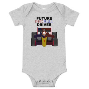 Peut inclure: Un body bébé gris avec une voiture de course de dessin animé et le texte "FUTURE REDBULL DRIVER" en rouge, bleu et noir.