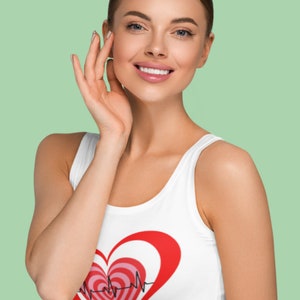 May include: White tank top featuring a large red heart design with concentric heart shapes in pink and red. A black electrocardiogram line runs through the heart. The tank top is sleeveless and has a scoop neck.