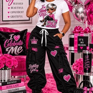 Può includere: Una t-shirt bianca a maniche corte con la grafica di un personaggio stilizzato e il testo I Celebrate Me e 50th Birthday, abbinata a pantaloni cargo neri con coulisse, toppe a forma di cuore rosa, icone a corona e il testo Birthday Girl.