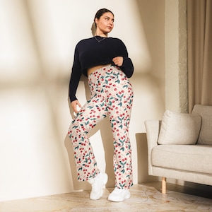 May include: A woman wearing a navy blue long-sleeved shirt and cream-colored pants with a cherry print. The pants are flared and have a high waist.