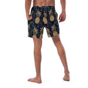 May include: A pair of black swim trunks with a pineapple print. The trunks have an elastic waistband and a drawstring.