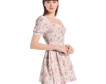 May include: A white dress with a pink floral print and a square neckline. The dress has short puff sleeves and a fitted bodice. The skirt is a-line and falls to just above the knees.