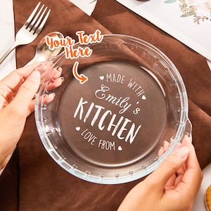 May include: A clear glass pie plate with the text "Made with Emily's Kitchen Love From" etched on the bottom.