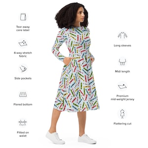 May include: A light blue midi dress with a colourful crayon print. The dress has long sleeves, a fitted waist, and a flared bottom. It features side pockets and a flattering cut.