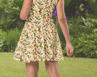 May include: A white dress with a sleeveless bodice and a full skirt. The dress features a pattern of orange citrus fruit and green leaves.