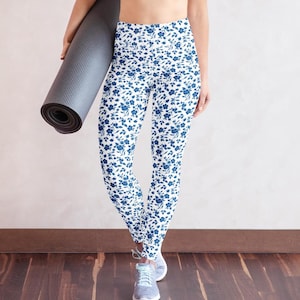 May include: White yoga leggings with a blue floral pattern. The leggings are high-waisted and have a tight fit.