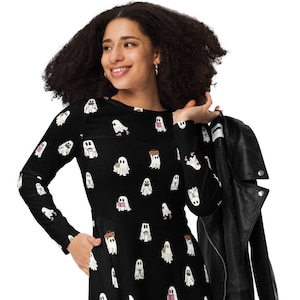 May include: A black long-sleeved dress with a white ghost print. The ghosts are holding books, coffee cups, and boomboxes. The dress has a fitted bodice and a flared skirt.