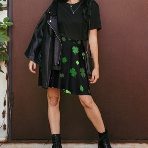 May include: A black skater skirt with a green shamrock print. The skirt is worn with a black t-shirt and a black leather jacket.