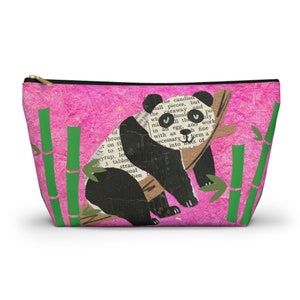 May include: A pink zippered pouch with a black and white panda bear holding onto a bamboo branch. The background is pink with green bamboo stalks and small white flowers.