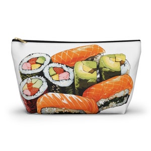 May include: A white zippered pouch with a colorful illustration of sushi rolls. The sushi includes salmon, avocado, and imitation crab.