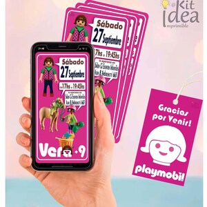 May include: A hand holding a smartphone displaying a pink invitation with Playmobil figures and text. Several matching invitation cards are stacked behind the phone. A pink tag with the words "Gracias por Venir!" and the Playmobil logo is also visible.