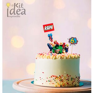 Op de afbeelding: Een witte cake met kleurrijke sprinkels en een Lego-thema topper. De topper heeft een groep superhelden, waaronder Hulk, Spiderman, Iron Man en Captain America. De cake heeft ook een rode vlag met de naam "Rami" en een blauw en geel spandoek met het nummer "6" erop.