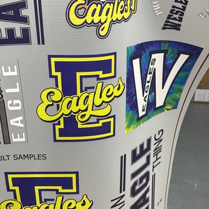 K&ouml;nnte beinhalten: Ein grauer Hintergrund mit einem blauen und gelben 'E' f&uuml;r Eagles-Logo. Das Logo wird in verschiedenen Gr&ouml;&szlig;en und Stilen wiederholt. Der Text 'Property of Wesley Chapel Eagles' ist ebenfalls sichtbar.