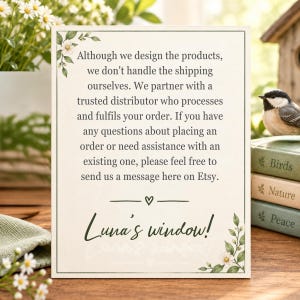 May include: A rectangular white sign with a thin black border, decorated with green leaves and white flowers in the corners. The text reads: Although we design the products, we don't handle the shipping ourselves. Luna's window!