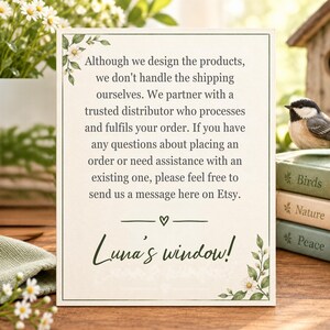 Puede incluir: Un letrero rectangular blanco con un borde negro fino, decorado con hojas verdes y flores blancas en las esquinas. El texto dice: Although we design the products, we don't handle the shipping ourselves. Luna's window!