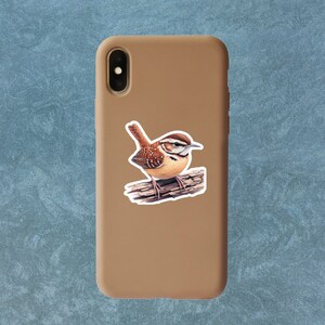 Carolina Wren profile vinyl sticker applied to a tan phone case. The phone case is shown on a plain surface.