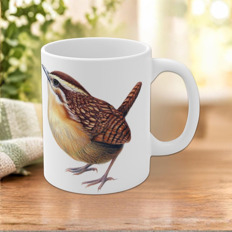 Puede incluir: Una taza de cer&aacute;mica blanca con una ilustraci&oacute;n detallada de un choch&iacute;n de Carolina. El ave tiene plumas de color marr&oacute;n, canela y crema, un pico puntiagudo y una peque&ntilde;a cola erguida. La taza tiene un acabado liso y un asa curva.