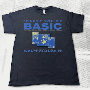Könnte beinhalten: Schwarzes T-Shirt mit blauem Text "'CAUSE YOU'RE BASIC" und drei blau getönten Bildern. Unter den Bildern steht der Text "WON'T CHANGE IT". Das T-Shirt hat einen Rundhalsausschnitt.