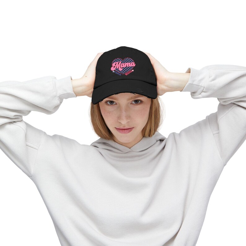 May include: A black baseball cap with a pink heart and the text "Mama" in a retro font. The heart has a checkered pattern.