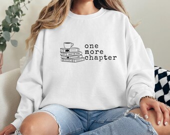 May include: White sweatshirt with a black graphic of a stack of books and a coffee cup. The text "one more chapter" is printed below the graphic.