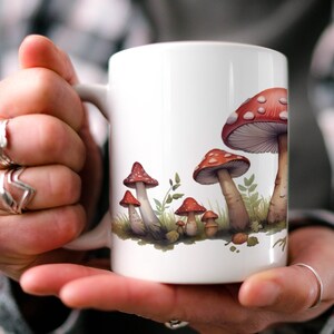 May include: White ceramic mug with a red and white mushroom design. The mushrooms are arranged in a row along the bottom of the mug.