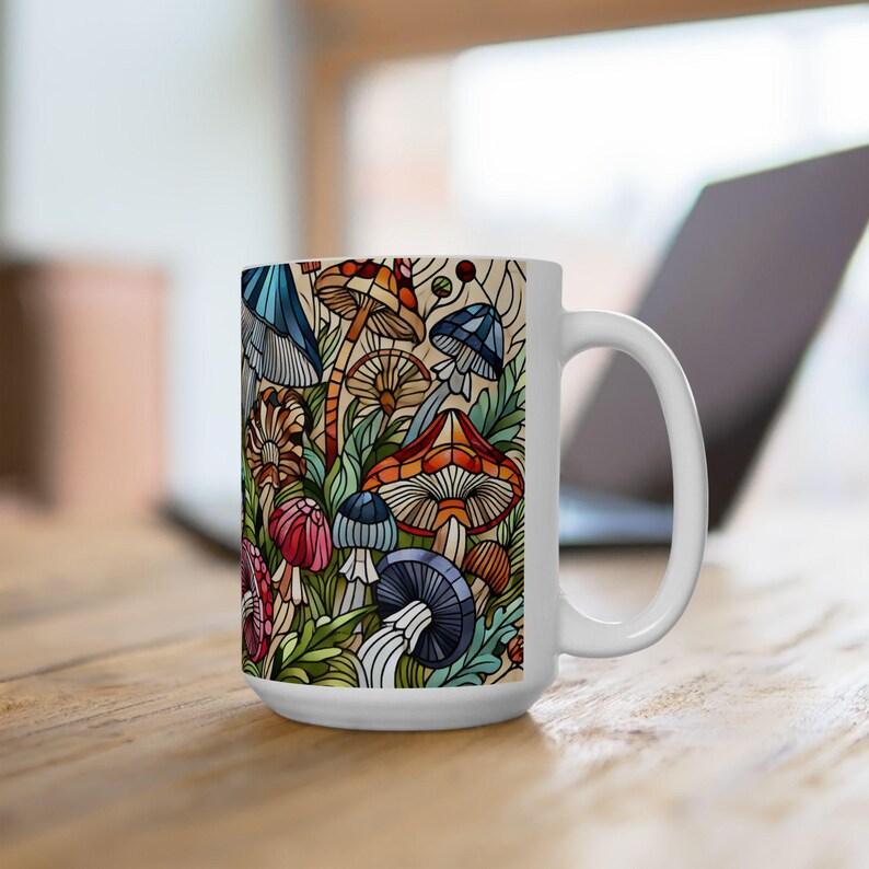 K&ouml;nnte beinhalten: Wei&szlig;e Keramiktasse mit einer bunten Illustration von Pilzen und Bl&auml;ttern. Die Tasse hat einen Henkel auf der rechten Seite.