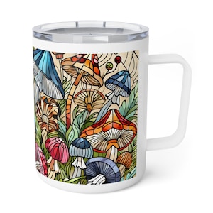 K&ouml;nnte beinhalten: Wei&szlig;e Keramiktasse mit einem bunten Bleiglasmuster aus Pilzen und Bl&auml;ttern. Die Tasse hat einen Henkel und einen Deckel.