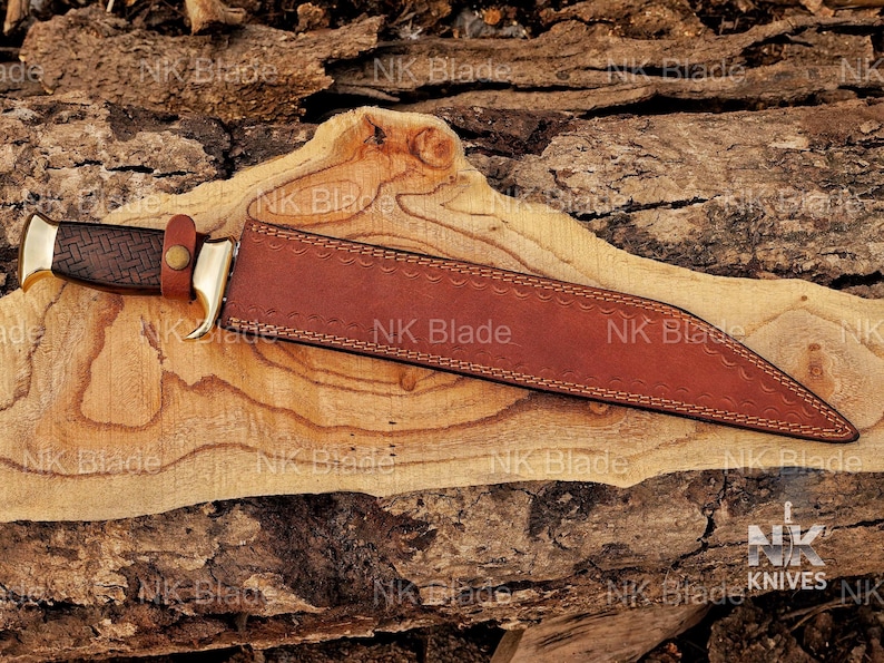 May include: A fixed-blade knife with a dark brown textured handle, a brass bolster, and a brown leather sheath. The sheath features decorative stitching along the edges and a small leather strap with a brass snap button securing the handle in place.