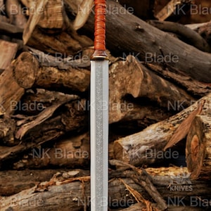 May include: A double-edged sword featuring a silver-toned blade with an intricate etched pattern running down the center. The hilt consists of a brown leather-wrapped grip, a rounded wooden pommel with swirling grain, and a brass-colored guard.