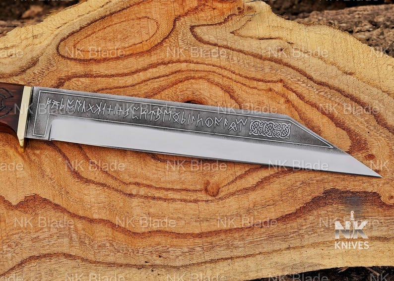 May include: A fixed-blade knife with a dark wooden handle and a brass bolster. The steel blade features an etched pattern of runic characters along the spine and a decorative Celtic knot design near the pointed tip, with a polished cutting edge.