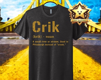 Op de afbeelding: Een donkergrijs T-shirt met een gouden afbeelding waarop staat: "Crik (krik) - zelfstandig naamwoord Een kleine rivier of beek. Gebruikt in Pittsburgh in plaats van "creek.""