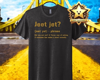 Op de afbeelding: Een donkergrijs T-shirt met een gouden afbeelding met de tekst "Jeet jet? (jeet yet) - phrase Did you eat yet? A Yinzer way of asking if someone has eaten a meal recently."