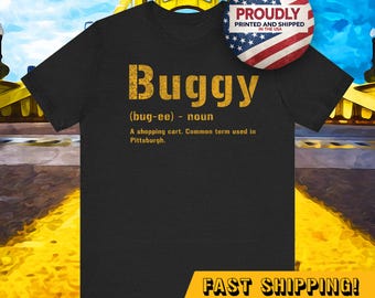May include: A black t-shirt with gold text that reads "Buggy (bug-ee) - noun A shopping cart. Common term used in Pittsburgh." The shirt also has the text "PROUDLY PRINTED AND SHIPPED IN THE USA" and "FAST SHIPPING!" in gold text.