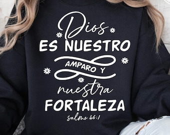 May include: A black sweatshirt with white text that reads "Dios ES NUESTRO AMPARO Y nuestra FORTALEZA Salmo 46:1". The sweatshirt has a crew neck and long sleeves. The brand name "MESADESIGNS" is in the upper right corner.