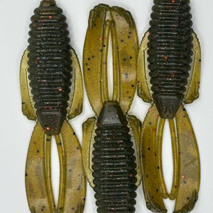 May include: Three green and black soft plastic fishing lures with red glitter. The lures have a segmented body and two pairs of appendages.